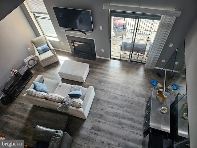 living room with baseboards, wood finished floors, and a fireplace with flush hearth