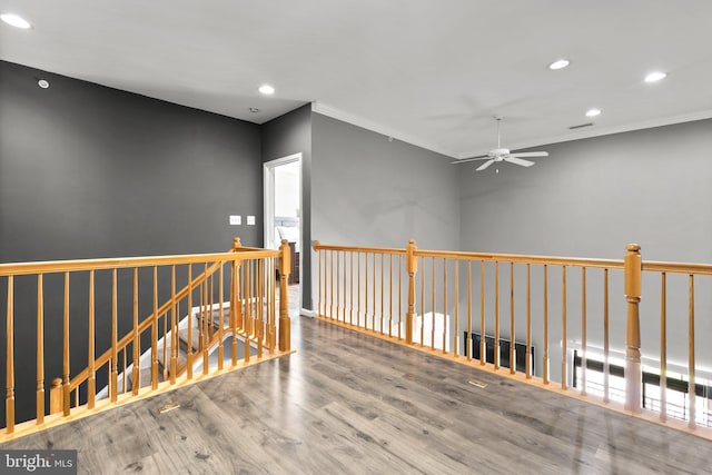 hallway with wood finished floors, ornamental molding, recessed lighting, and an upstairs landing