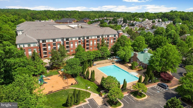 drone / aerial view of a pool and a heavily wooded area