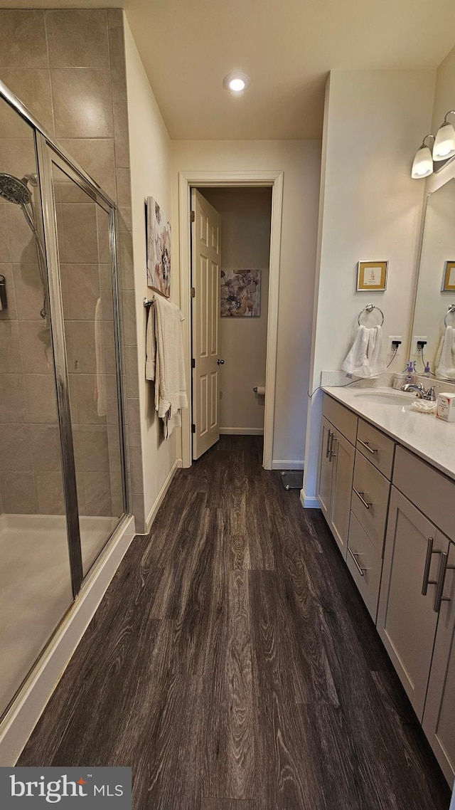 full bath featuring vanity, wood finished floors, baseboards, recessed lighting, and a stall shower