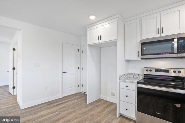 1011 Southwood Dr, Shippensburg, PA 17257 - kitchen with stainless steel appliances, light wood-type flooring, baseboards, white cabinets, and light stone countertops