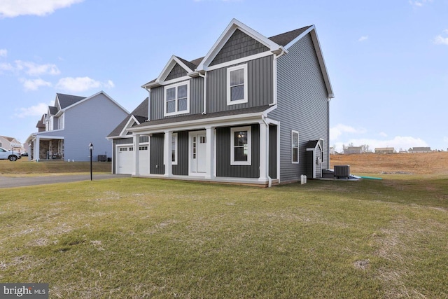 1011 Southwood Dr, Shippensburg, PA 17257 - view of front facade featuring board and batten siding, covered porch, a front yard, central AC, and driveway