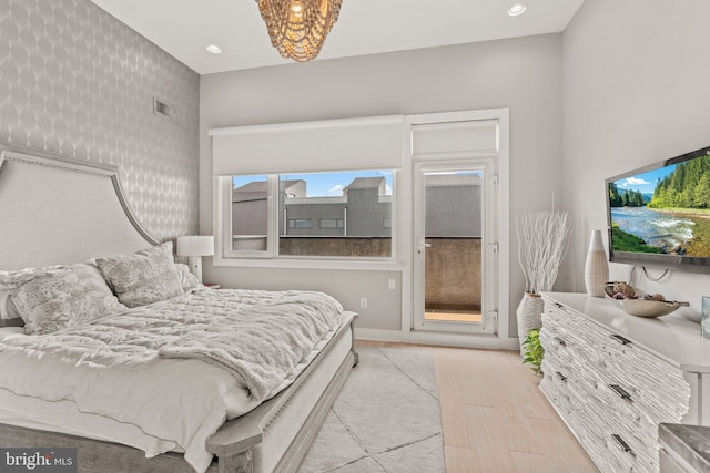 bedroom featuring access to exterior, baseboards, wallpapered walls, wood finished floors, and visible vents