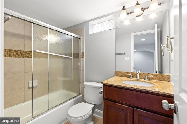 bathroom featuring vanity, bath / shower combo with glass door, and toilet