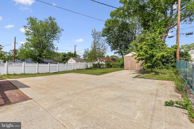 view of patio / terrace featuring fence, an outbuilding, concrete driveway, and a shed