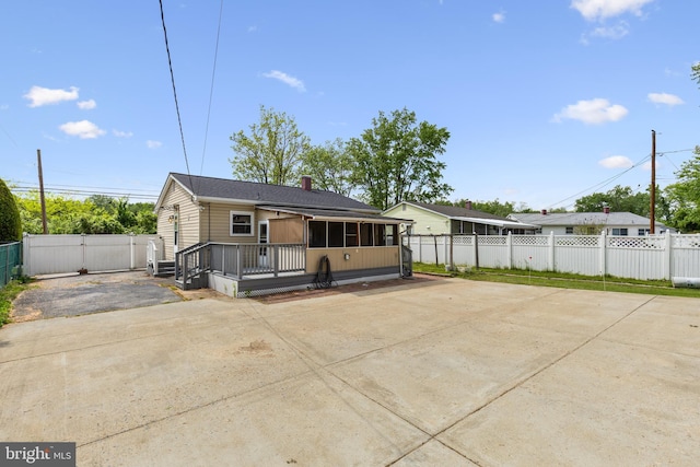 rear view of house featuring fence, a gate, and driveway