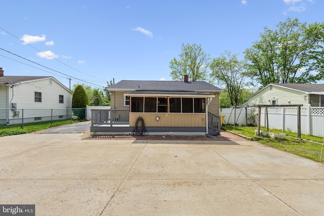 rear view of property with a sunroom, a shingled roof, fence, and a chimney