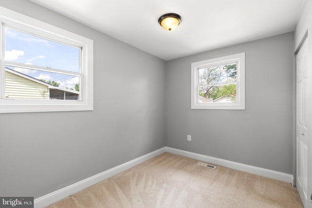 carpeted spare room featuring visible vents and baseboards