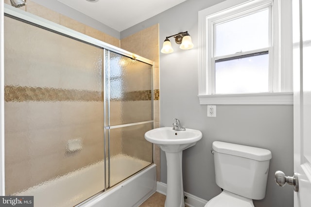 full bathroom featuring toilet, combined bath / shower with glass door, and a sink