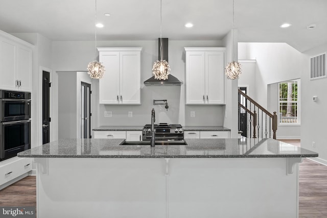 14875 Buckingham Ct, Issue, MD 20645 - kitchen featuring wall chimney exhaust hood, a kitchen island with sink, dark wood finished floors, white cabinetry, and recessed lighting