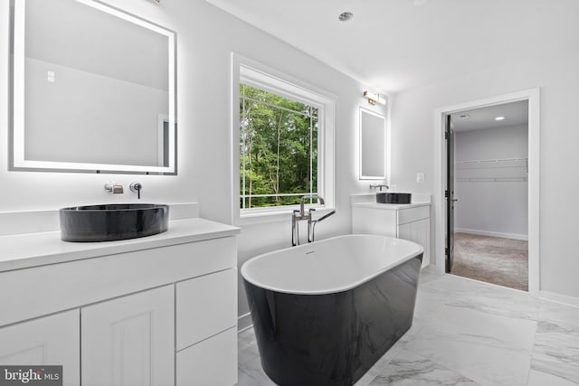 14875 Buckingham Ct, Issue, MD 20645 - bathroom with baseboards, marble look tiles, a freestanding tub, two vanities, and a spacious closet