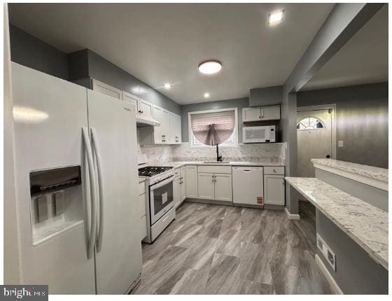 7204 Croydon Rd, Baltimore, MD 21207 - kitchen with white appliances, backsplash, light stone countertops, under cabinet range hood, and a sink