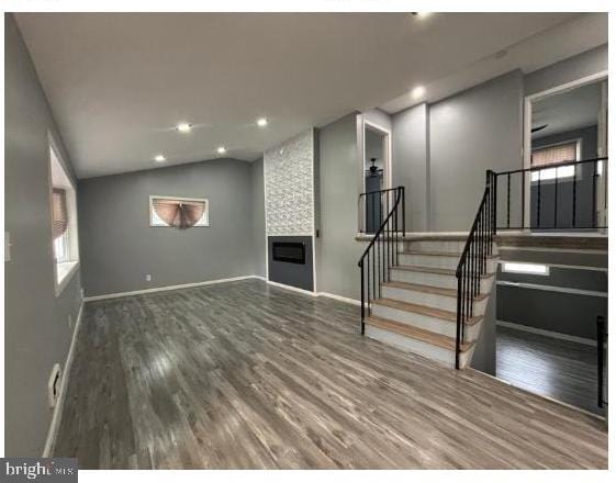 7204 Croydon Rd, Baltimore, MD 21207 - unfurnished living room featuring wood finished floors, stairs, baseboards, a fireplace, and lofted ceiling