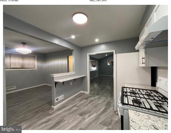 7204 Croydon Rd, Baltimore, MD 21207 - kitchen with gas range oven, under cabinet range hood, light countertops, white cabinetry, and recessed lighting