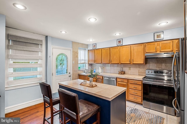 4037 Mitchell St, Philadelphia, PA 19128 - kitchen with a kitchen island, a breakfast bar, under cabinet range hood, appliances with stainless steel finishes, and backsplash