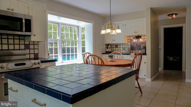 30 Woods Ln, Hanover, PA 17331 - kitchen with tile countertops, stainless steel microwave, backsplash, electric range oven, and a chandelier