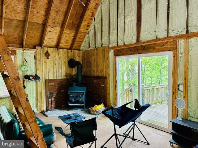 living area with a wood stove, wood walls, and high vaulted ceiling