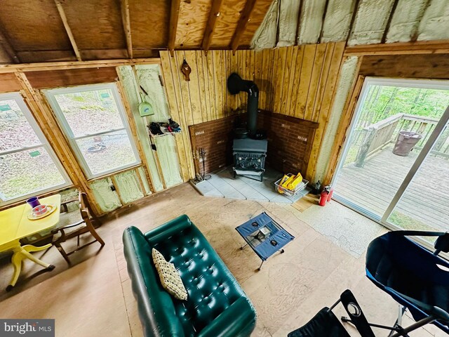 living area with plenty of natural light, a wood stove, and wood walls