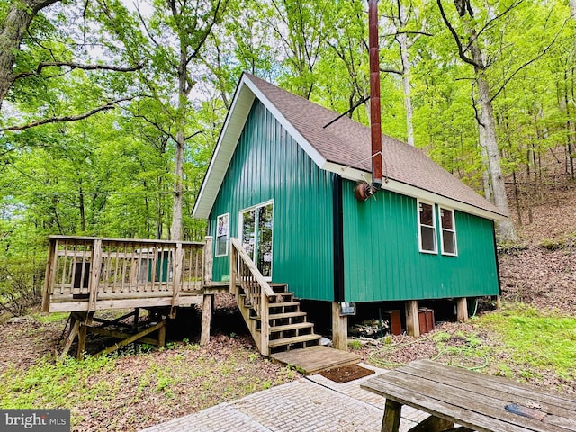 view of property exterior with a shingled roof and a wooden deck