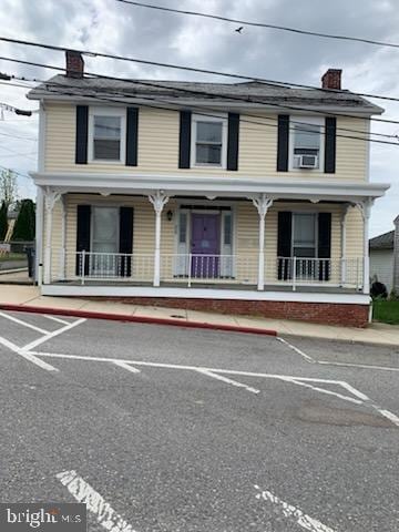 view of front of property featuring a chimney, a porch, and uncovered parking