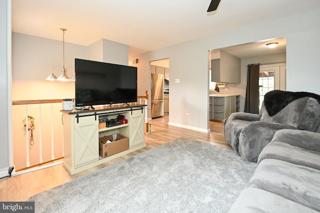living area featuring baseboards, visible vents, light wood-style flooring, and ceiling fan