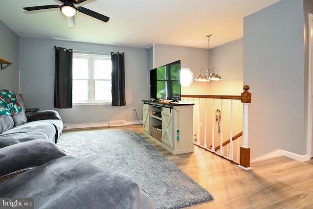 living room with baseboards, visible vents, light wood-type flooring, and ceiling fan with notable chandelier