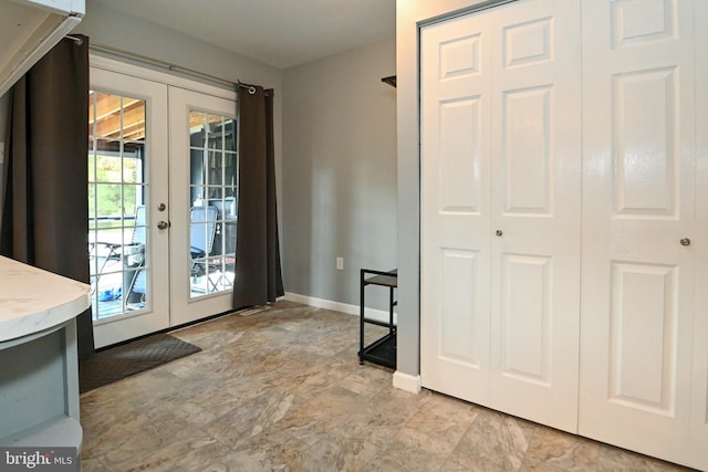 doorway featuring baseboards, stone finish flooring, and french doors