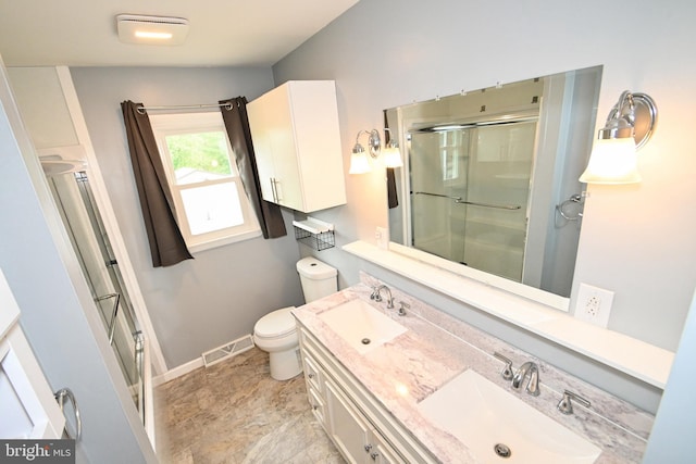 bathroom with toilet, visible vents, a shower with door, and a sink