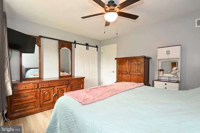bedroom with a ceiling fan, visible vents, and wood finished floors