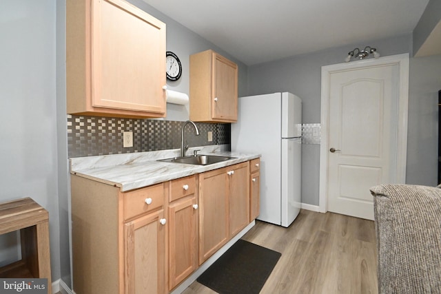 kitchen featuring a sink, freestanding refrigerator, light wood-type flooring, light brown cabinetry, and light countertops
