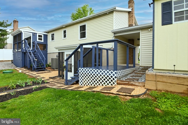 rear view of property with a sunroom, a chimney, a lawn, stairway, and entry steps