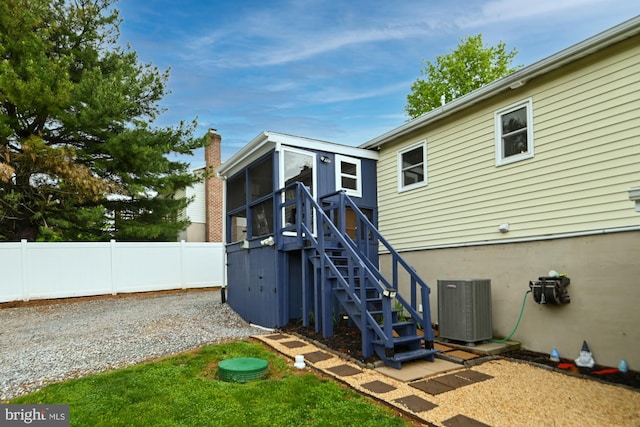 back of property with central AC unit, a sunroom, stairs, and fence