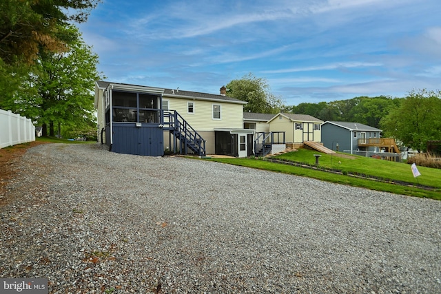 back of property featuring a sunroom, a chimney, fence, a lawn, and stairway
