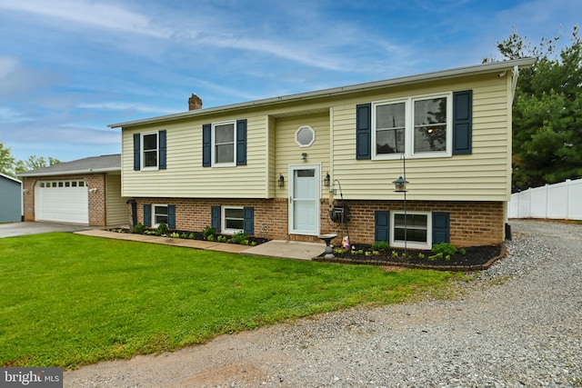 raised ranch with concrete driveway, an attached garage, fence, and a front yard