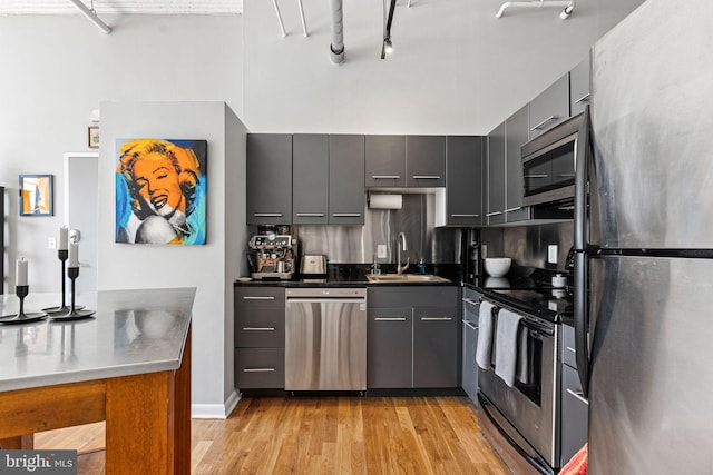 2200 Arch St Unit 409, Philadelphia, PA 19103 - kitchen featuring gray cabinets, a sink, light wood finished floors, and appliances with stainless steel finishes