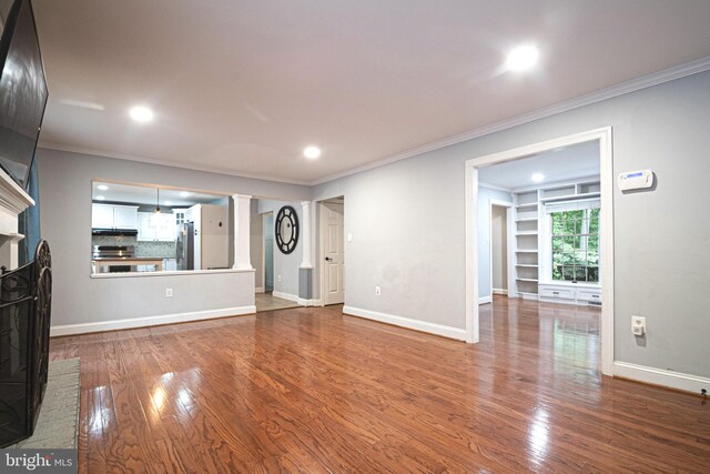 9190 Balsam Run, Bel Alton, MD 20611 - unfurnished living room featuring crown molding, wood finished floors, a brick fireplace, and decorative columns