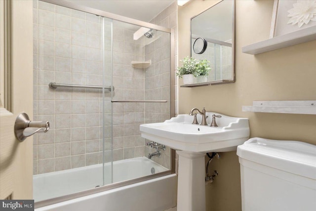 bathroom featuring combined bath / shower with glass door and toilet