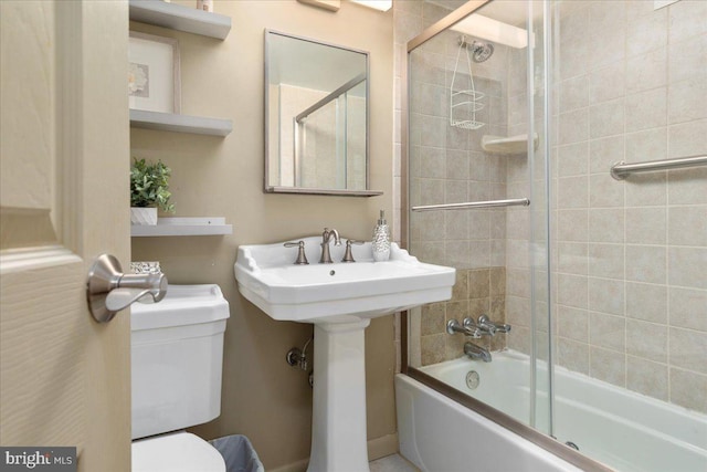 full bath with toilet, a sink, and bath / shower combo with glass door