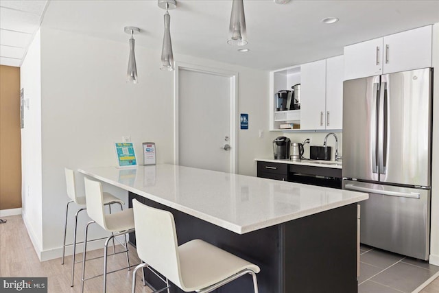 kitchen featuring a peninsula, freestanding refrigerator, open shelves, a breakfast bar area, and white cabinets