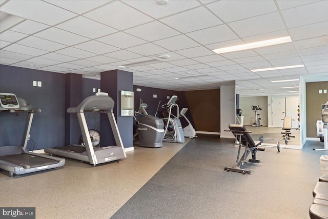 exercise room with a drop ceiling and baseboards