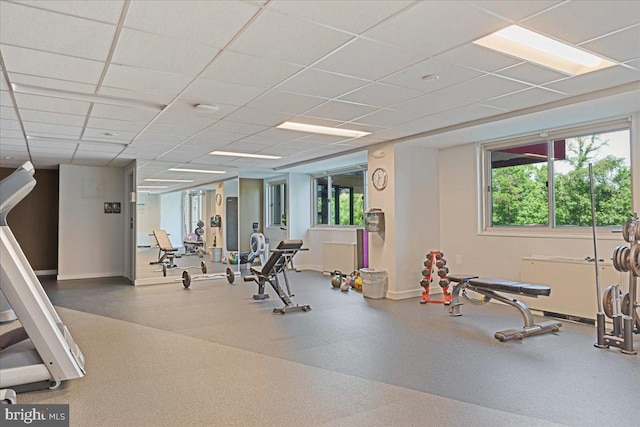 exercise room featuring a drop ceiling, baseboards, and a healthy amount of sunlight