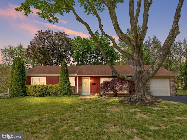 ranch-style house with a front lawn, brick siding, driveway, and a garage