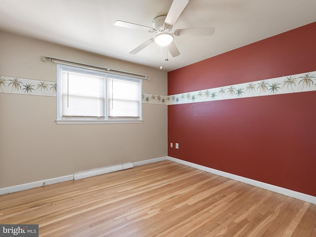 spare room with baseboards, wood finished floors, a ceiling fan, and a baseboard heating unit