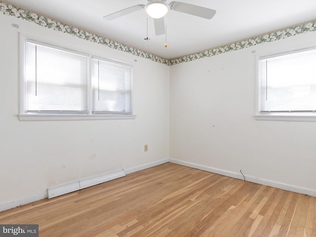 spare room featuring a ceiling fan, light wood-style floors, baseboards, and a baseboard radiator