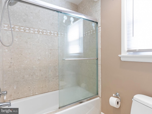 full bath featuring toilet and combined bath / shower with glass door