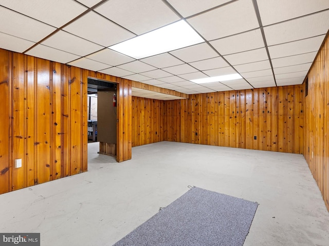 finished basement featuring a paneled ceiling and wood walls