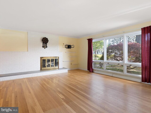 unfurnished living room featuring baseboard heating, a fireplace, and wood finished floors