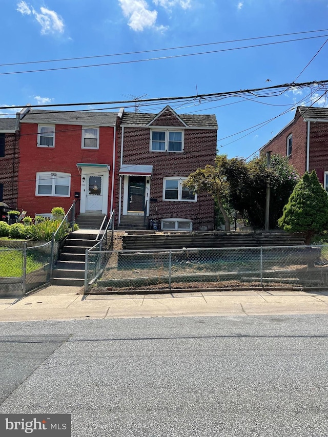 townhome / multi-family property featuring brick siding and a fenced front yard