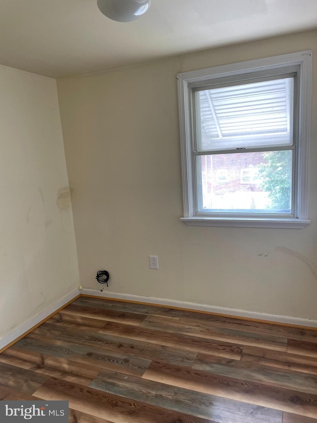 empty room featuring baseboards and dark wood-style floors