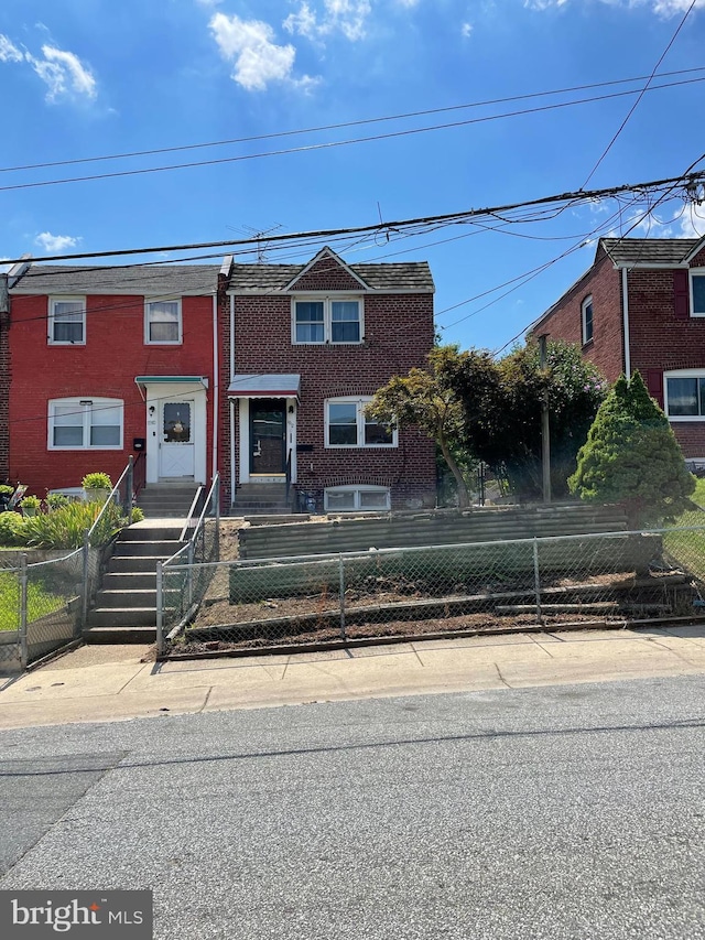 townhome / multi-family property with a fenced front yard and brick siding
